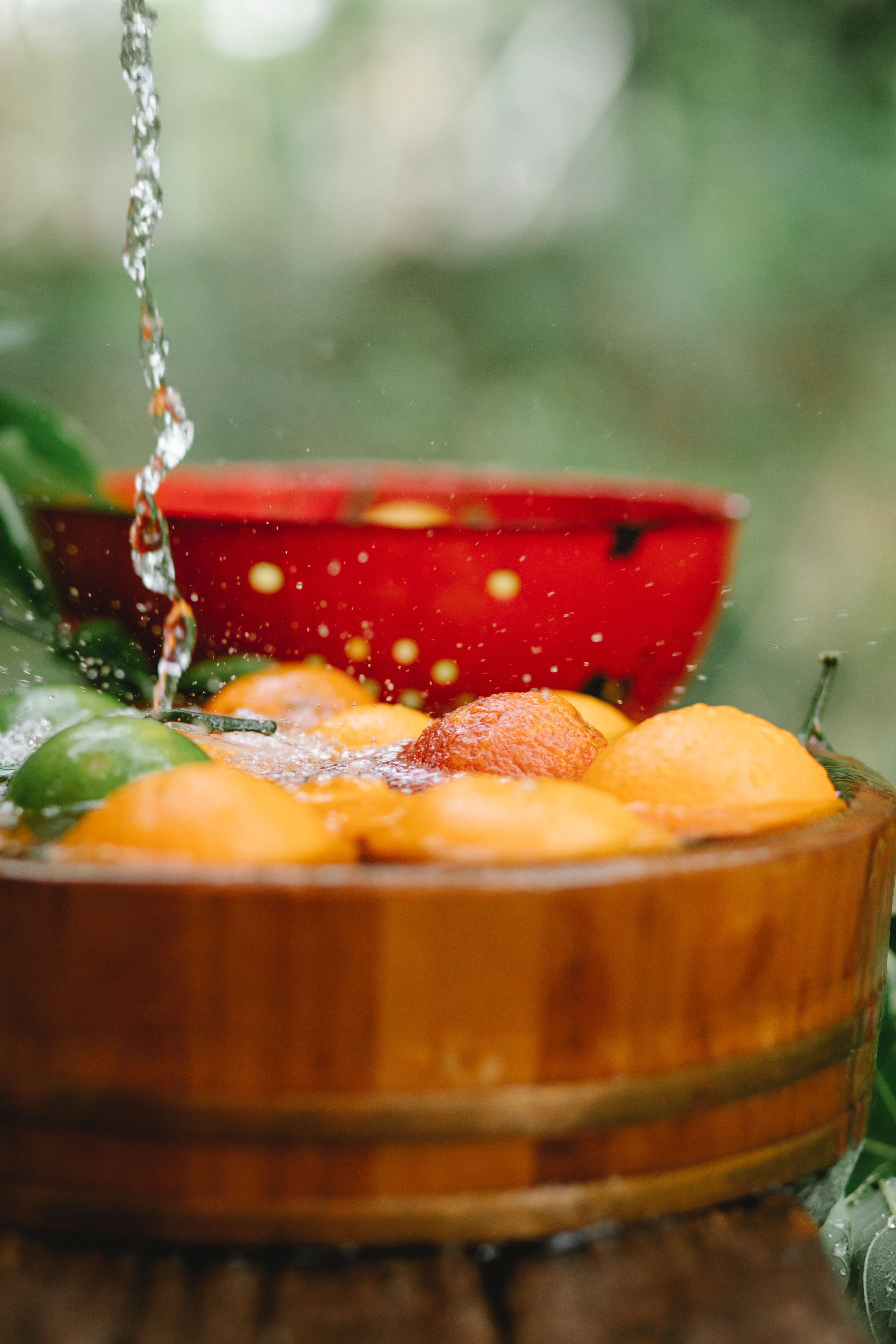 Bucket full with water and oranges in it. Water dripping from above