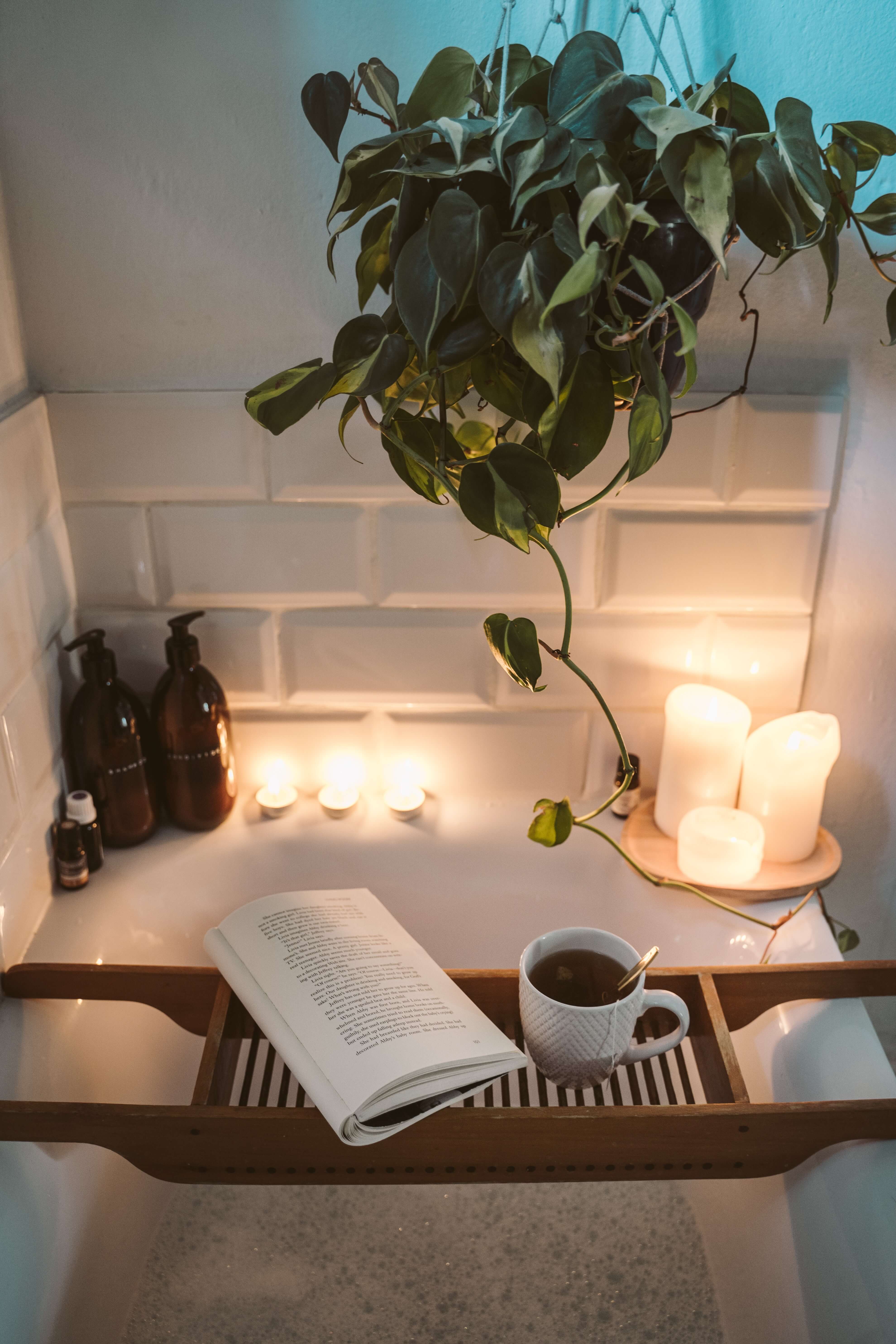 candles beside bathtub book and tea