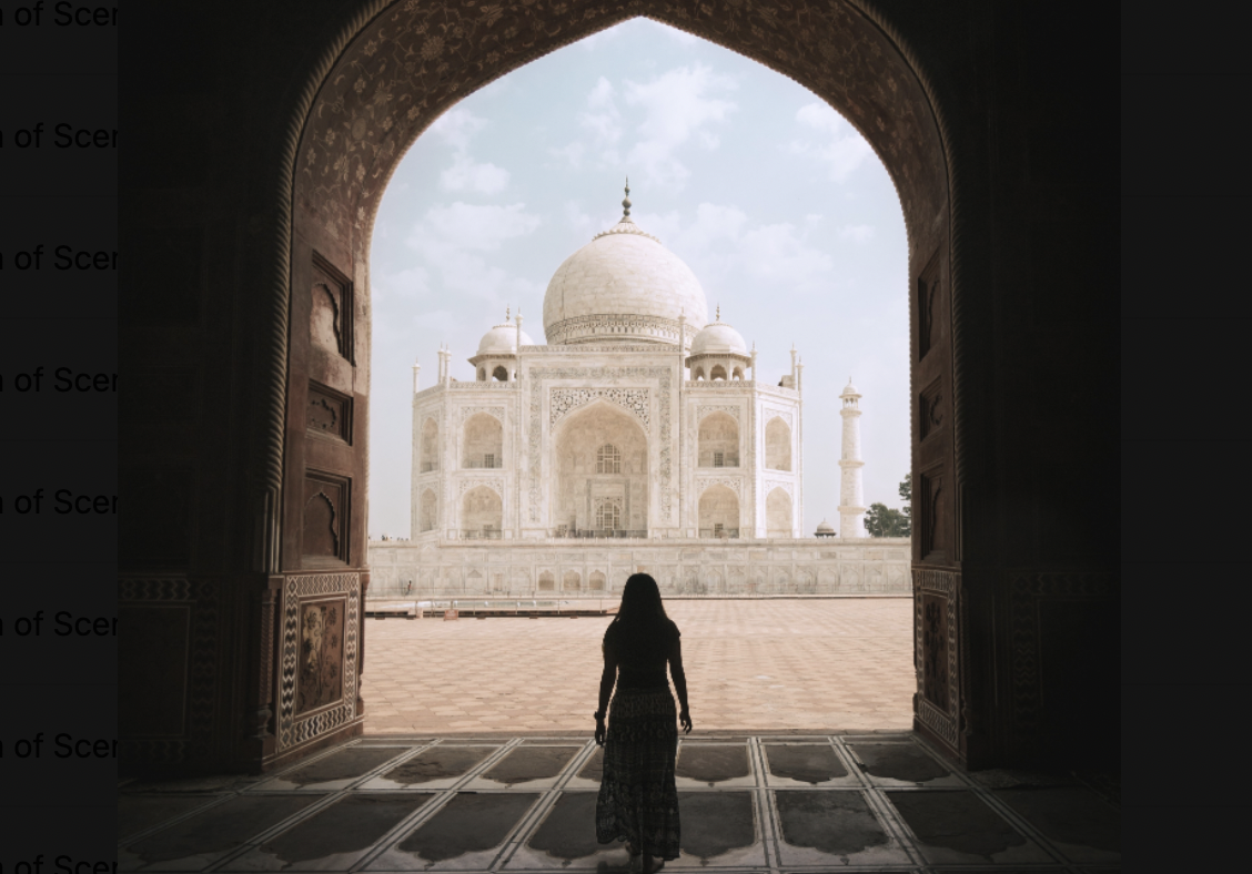 Woman walking out of a dark room  through a gateway into the bright outside facing the Tadj Mahal